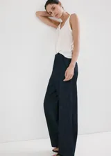 Pantalón largo wide leg de tiro medio confeccionado en tejido de algodón estilo denim, con bolsillos laterales y cierre frontal de botones, gancho y cremallera.