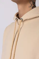 Buzo canguro color bordó con capucha y cordones ajustables. Presenta un bolsillo frontal tipo canguro y un pequeño parche rectangular con diseño gráfico en la manga derecha.