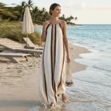 Vestido maxi de corte holgado, con tirantes finos y diseño de rayas verticales en tonos blanco, marrón y dorado.