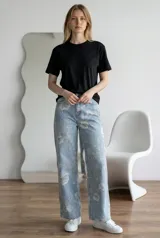 Jean de corte recto y tiro medio, confeccionado en denim celeste con estampado floral en tonos claros. Presenta cierre frontal con botón y bolsillos laterales y traseros.