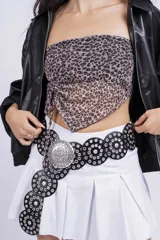 Minifalda negra de corte tableado con cinturón de cuero negro con hebilla plateada y tachas.