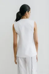 Chaleco sastrero blanco de lino, con cuello en V profundo y cierre cruzado con botones.