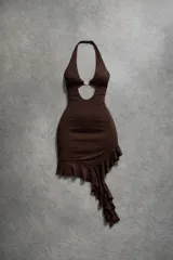Vestido corto color marrón, con diseño halter y abertura frontal decorada con un aplique de strass. Presenta un ruedo asimétrico con volados que se extienden hacia un lado.