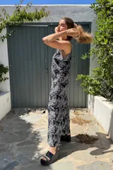 Mono largo confeccionado en fibrana con estampado de hojas blancas sobre fondo negro. Presenta breteles finos, escote en V y un calce holgado y fluido ideal para el verano.