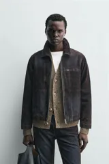 Cazadora de hombre de corte relajado, confeccionada en tejido con algodón de acabado flocado efecto terciopelo lavado, color marrón oscuro con efecto desgastado. Presenta cuello solapa, cierre frontal de cremallera, bolsillo con cremallera en el pecho y bolsillos laterales en la costura de la cadera.