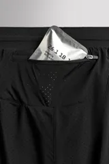 Short de running negro de tejido técnico perforado, ligero y elástico, con malla interior. Presenta cintura elástica ajustable con cordón interior, bolsillo trasero con cierre de seguridad y bajo con aberturas laterales.