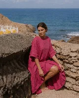 Vestido corto de lino color blanco, con mangas cortas amplias, escote redondo y diseño asimétrico más corto en la parte delantera y con volados en el ruedo.