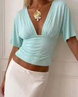 Top de color verde aqua con escote pronunciado en V, frunces en el busto y cintura marcada. Cuenta con mangas cortas amplias y de caída fluida.