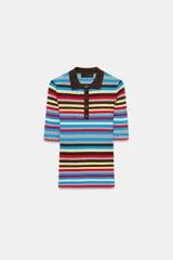 Jersey de punto de manga corta con diseño a rayas horizontales multicolor en tonos celestes, marrones, amarillos, rojos y grises. Presenta cuello polo marrón y cierre frontal con tres botones.