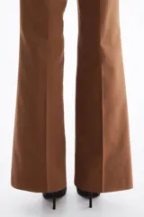 Pantalón bootcut color marrón, tiro alto, con pliegues frontales y cinturón elástico incluido con hebilla metálica redonda.