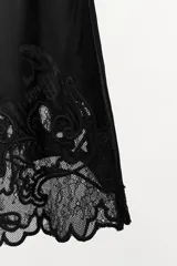 Top de tirantes finos cruzados en la espalda, con escote en pico. Confeccionado en viscosa, presenta detalles de bordados y aplicaciones de encaje a tono en el bajo, con una pequeña abertura lateral.