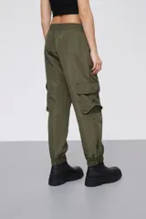 Babucha estilo cargo color verde oliva, confeccionada en tela técnica con acabado satinado. Presenta cintura elástica, bolsillos laterales con solapa y puños elásticos en los tobillos.