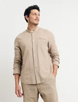Camisa de cuello mao y manga larga, confeccionada en una mezcla de lino y algodón. Presenta un diseño de corte recto con botones en tono natural y un bolsillo pequeño en el pecho.