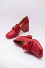 Zapato de cuero rojo con aplique decorativo en el empeine y tacón cuadrado.