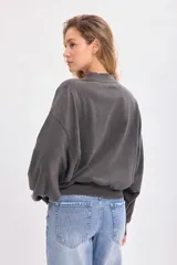 Buzo gris oscuro con efecto lavado, cuello redondo, hombros caídos y mangas abullonadas con puños ajustados.