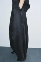 Jeans de tiro alto con diseño de pierna tipo balloon, confeccionados en denim de color gris oscuro con efecto lavado. Presentan costuras verticales marcadas a contraste, bolsillos laterales ocultos y cierre lateral con cremallera.