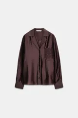 Camisa de manga larga color marrón oscuro, con cuello solapa, escote pico y bajo asimétrico. Presenta un bolsillo plastrón en el delantero con bordado combinado a tono.