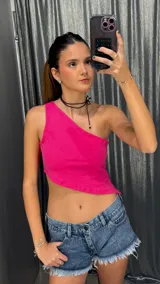 Top de un solo hombro en color fucsia, con corte asimétrico y diseño corto tipo crop top.