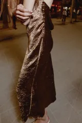 Vestido midi lencero de color marrón, con escote fluido en el delantero y la espalda, tirantes finos y tejido con efecto arrugado.
