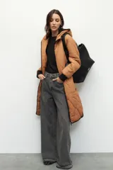 Campera de nylon larga oversized color negro, con capucha, tres bolsillos externos y uno interno. De tela capitoneada, con puños en las mangas y forro polar.