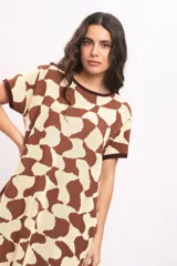 Vestido tejido de punto con diseño geométrico abstracto en marrón y beige, cuello redondo y mangas cortas con ribetes en tono oscuro.