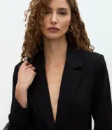 Blazer de sastrería marca Cortelle con diseño entallado tipo reloj de arena, solapas clásicas, cierre frontal de un botón, bolsillos con solapa y mangas largas.