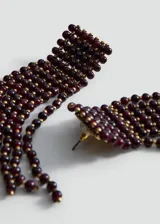Aros colgantes largos confeccionados con cuentas de cristal borgoña y pequeñas cuentas doradas, con base rectangular y flecos de cuentas colgantes.