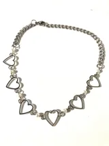 Gargantilla plateada con cadena de eslabones y dijes de corazones calados, unidos por pequeñas perlas blancas.