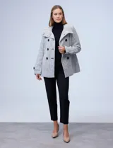 Tapado corto de lana y poliéster, con tejido tweed en tonos blanco y negro. Presenta cuello con solapa, doble abotonadura frontal en color negro y bolsillos verticales.