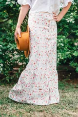 Falda larga de algodón con estampado floral, tiro alto y cierre frontal con botones de madera. Presenta un diseño evasé con un volante en el bajo.