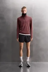 Sudadera técnica color vino tinto, de manga larga, con cuello subido y cierre frontal de cremallera. Presenta un bolsillo frontal con cierre de cremallera oculta en costura y detalle de logo estampado. El tejido tiene estructura waffle en el interior.