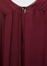 Blusa de viscosa color bordó, con diseño semitransparente, cuello drapeado con adorno de fular y mangas largas con puños elásticos.