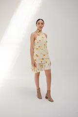 Minivestido color crema con estampado de flores amarillas, cuello halter y falda con volados.