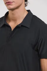 Chomba deportiva de manga corta, color negro, con cuello polo y cierre frontal de tres botones. Confeccionada en tejido técnico ultra liviano, fresco y respirable con alta elasticidad.