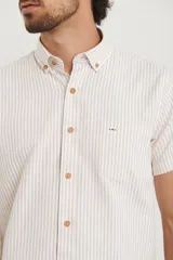 Camisa de manga corta a rayas verticales blancas y celestes, con cuello abotonado y bolsillo en el pecho.