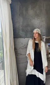 Ruana tejida a mano en hilo de color azul marino, con diseño liviano, textura abierta y terminaciones con flecos en los extremos.