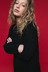 Sweater de tejido de punto negro con tramas de ochos en las mangas y laterales, cuello redondo a la base y mangas largas.