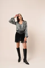 Blusa azul marino con estampado de hojas doradas, escote en V y mangas largas acampanadas.