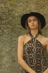 Vestido largo de corte recto con estampado abstracto en tonos marrón y beige, cuello halter y espalda descubierta.