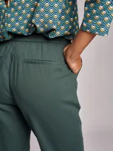 Pantalón de vestir verde oscuro, de corte recto, con cintura elástica ajustable con cordones, bolsillos laterales y ruedo con dobladillo.