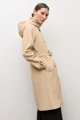 Trench clásico color beige, con cuello alto, capucha desmontable, cierre frontal de botones marrones, bolsillos ribeteados y cinturón ajustable con hebilla.