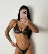 Conjunto de lencería de dos piezas confeccionado en tul transparente con estampado animal print tipo cebra aterciopelado en color negro. Incluye un corpiño triangular sin aro con breteles regulables y una bombacha tipo tanga a juego con detalles de argollas metálicas en los laterales.