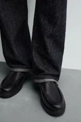 Zapato tipo Mary Jane color negro, con cierre mediante hebilla lateral, parte superior fabricada en piel, detalle de bordón en el empeine, horma redonda y suela con volumen.