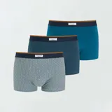 Pack de tres boxers de algodón elastizado, uno liso color celeste, uno con estampado geométrico azul oscuro sobre celeste y otro con estampado geométrico celeste sobre blanco. Todos tienen cintura elástica con logo de la marca.