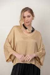 Blusa italiana de viscosa color beige, de calce holgado, con escote en V y detalle de lurex. Presenta mangas tres cuartos y diseño fluido.