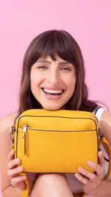 Bandolera color bordó con diseño texturizado geométrico en el frente, bolsillo frontal con cierre, bolsillo trasero con cierre y compartimento principal con divisiones. Incluye correa extensible.