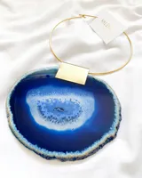 Collar con aro rígido dorado y dije de ágata azul con borde irregular.