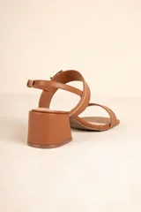 Sandalia negra de símil cuero con taco ancho y tiras ajustables con hebilla metálica. Presenta una tira ancha sobre los dedos y una tira fina con hebilla que sujeta el tobillo.