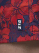 Short de baño con estampado botánico en tonos naranja y coral, con cintura elástica ajustable mediante cordón y malla interior para mayor soporte.