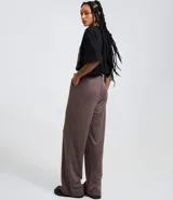 Pantalón wide leg de sastrería en color marrón con diseño de raya de tiza. Presenta cintura fija, cierre tradicional y pliegues frontales que aportan estructura y caída fluida.